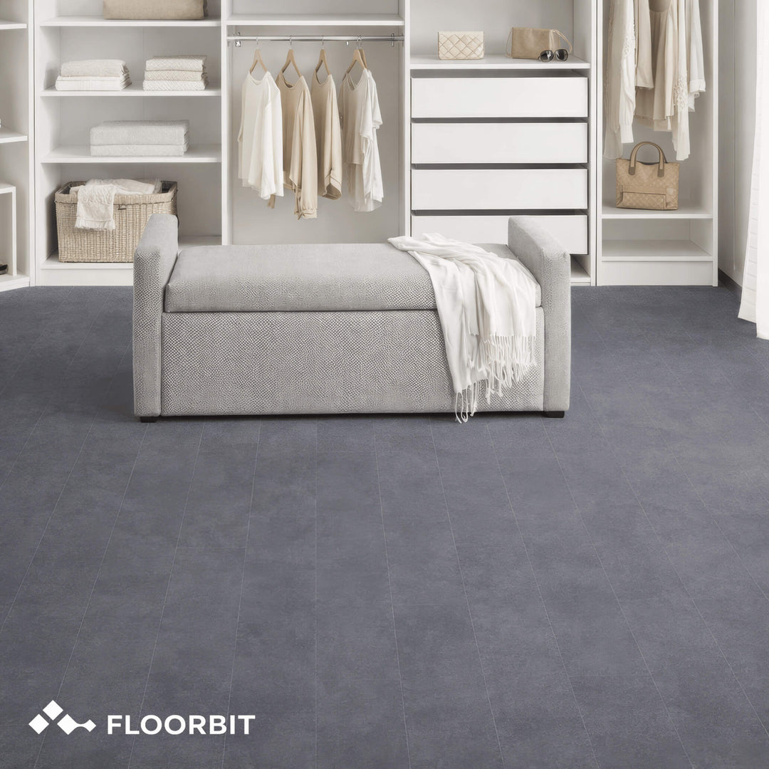 Waterblock X Joku dark grey stone-look floor in a wardrobe room with shelves and a bench, featuring the Floorbit logo.