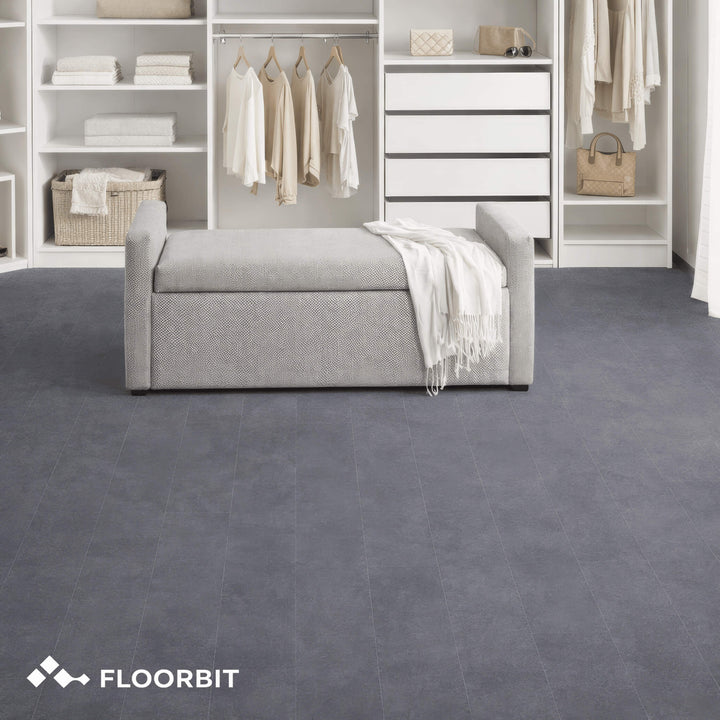Waterblock X Joku dark grey stone-look floor in a wardrobe room with shelves and a bench, featuring the Floorbit logo.