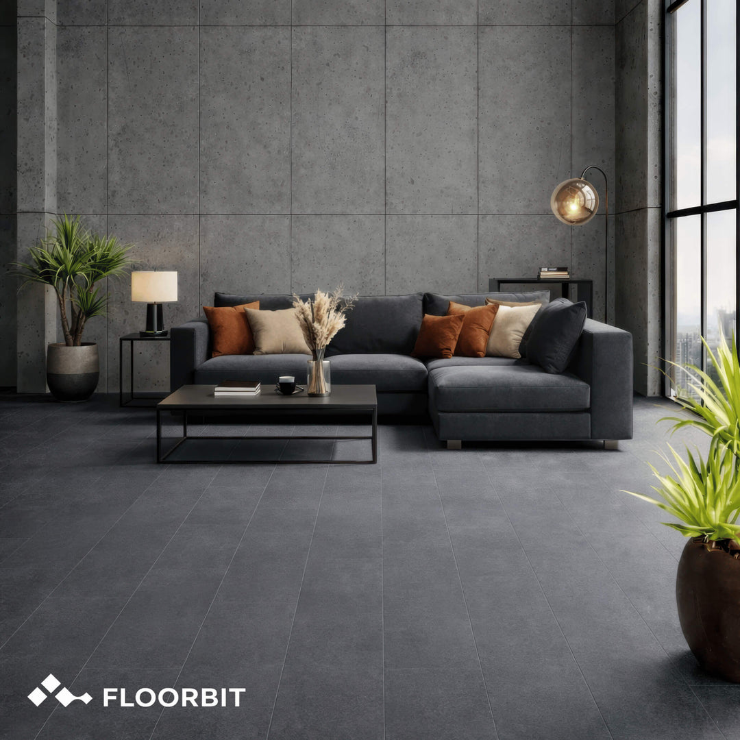 Modern living room with Waterblock X Joku dark grey stone-look floor, grey sectional sofa, coffee table, and decorative elements. FLOORBIT branding visible.