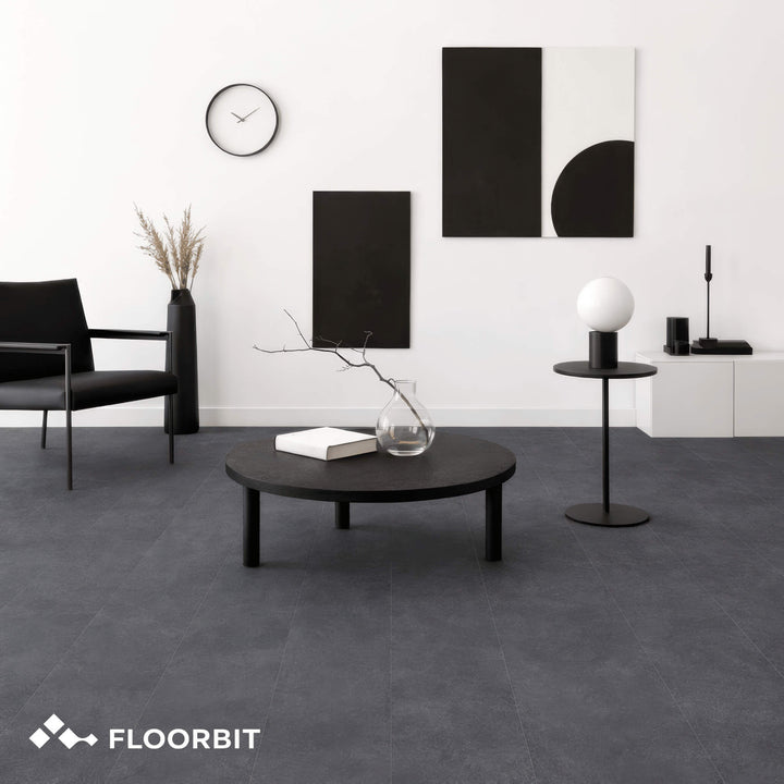 Modern living room with black furniture and Waterblock X Joku dark grey stone-look floor, featuring the Floorbit brand.